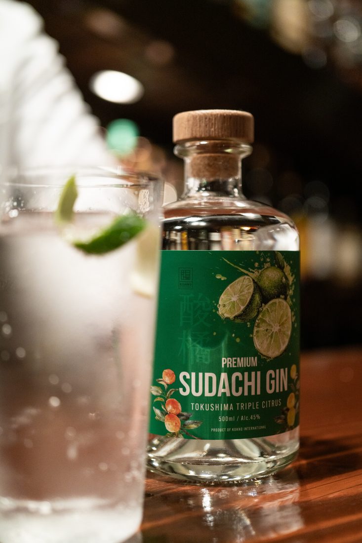 Premium Sudachi Gin のボトルと、すだちを浮かべたジントニック